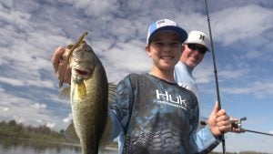 a kid holding a big fish with his dad